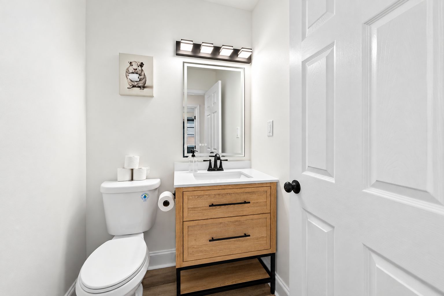 Een compacte badkamer met toilet, wastafel, spiegel en een houten kastje.
