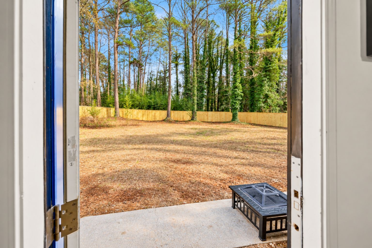 Un jardin avec une clôture en bois, un espace patio et une vue sur une forêt.
