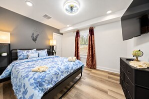 A modern bedroom with a bed, bedside lamps, a flat-screen TV, a dresser, and a globe.