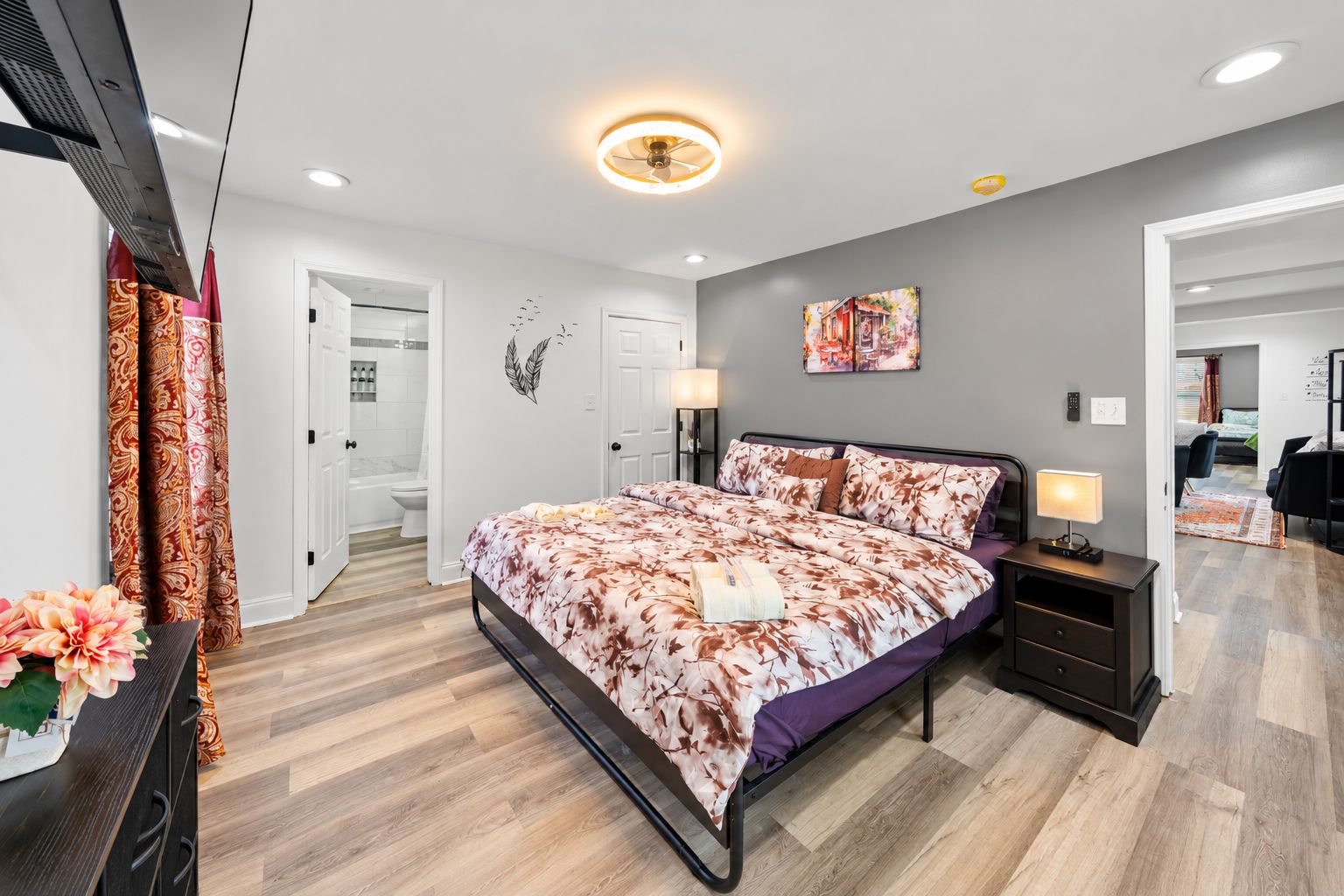A modern bedroom with a bed, bedside tables, and a bathroom visible through an open door.
