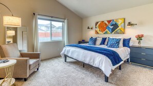 A bedroom with a bed, a chair, a desk, a lamp, a ceiling fan, and a window. - Heart of Sisters Suite (Sisters)