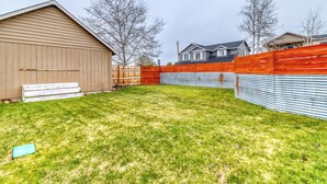 A backyard with a wooden shed, a metal fence, and a grassy lawn. - Heart of Sisters Suite (Sisters)