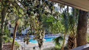 A pool area with lounge chairs and palm trees. - 34 Forest Gardens: Walk to Beach, Pool, Free Bikes (Hilton Head Island)