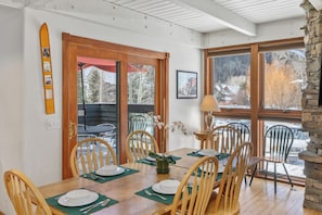 A dining area with wooden chairs, a wooden table, and a view of a snowy landscape through large windows. - 6 Bd, 5 Ba Telluride Condos on the River Trail, Connected, Sleeps 16 (Telluride)