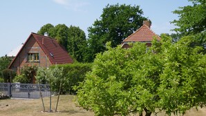 A residential area with two brick houses, a wooden fence, and a well-maintained lawn. - Ferienhaus in Fehmarn OT Kopendorf (Fehmarn)