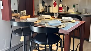 A modern kitchen with dark wooden cabinets, a built-in microwave, and a dining area with a table and chairs. - NR APART Bellas Artes (Santiago)