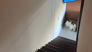 A staircase with a view of a room at the top, a wooden door, and a wall-mounted object. - NR APART Bellas Artes (Santiago)
