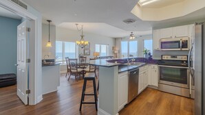Une cuisine moderne avec des meubles blancs, un îlot central et des appareils électroménagers en acier inoxydable.