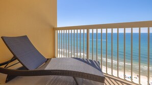 A balcony with a wicker chair and a view of the beach. - 1409E VIP Parking Spot + Beach Service! (Panama City Beach)