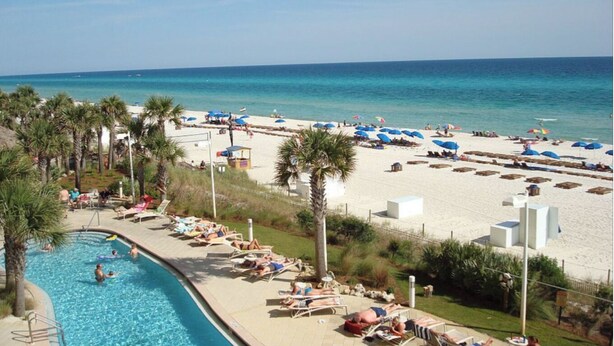 A resort with a swimming pool, beach area with umbrellas, and palm trees. - 1409E VIP Parking Spot + Beach Service! (Panama City Beach)