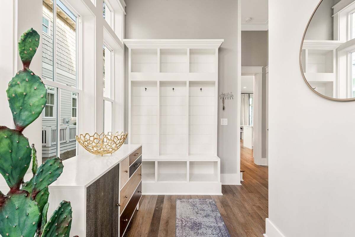 A modern hallway with a built-in bench, a cactus plant, and a mirror on the wall.