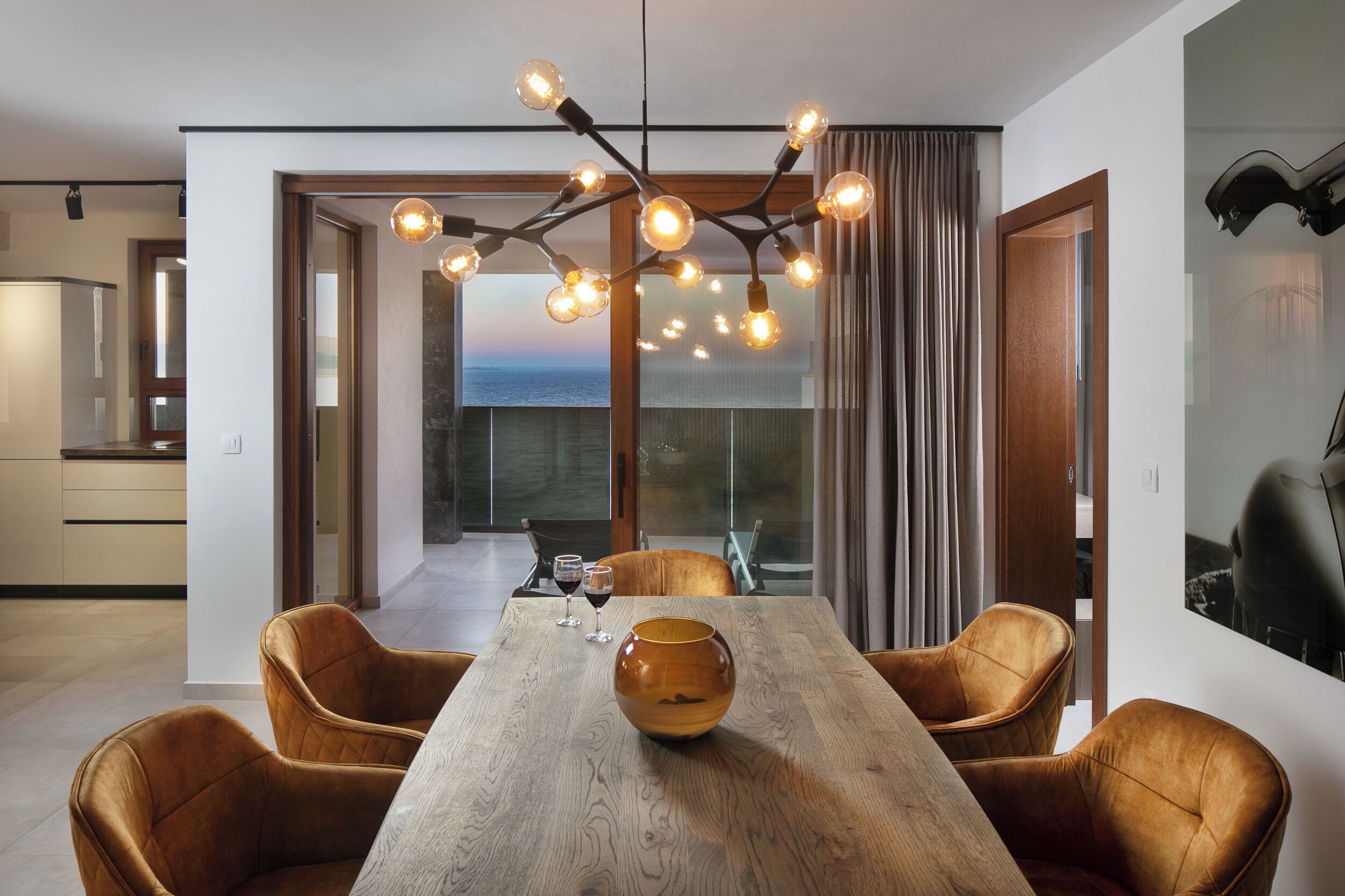 A modern dining area with a wooden table, leather chairs, and a unique light fixture.
