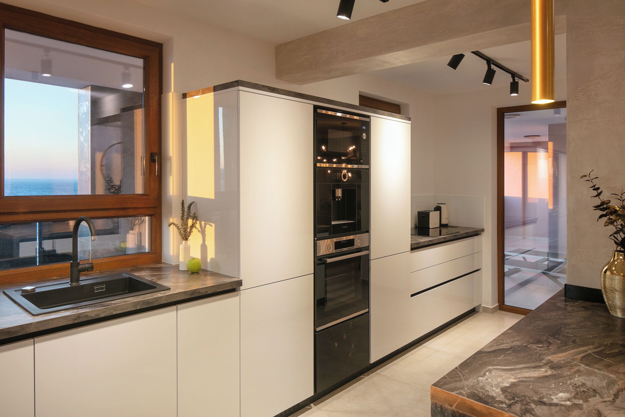 Una cucina moderna con forno integrato, lavello e finestra con vista sul mare.