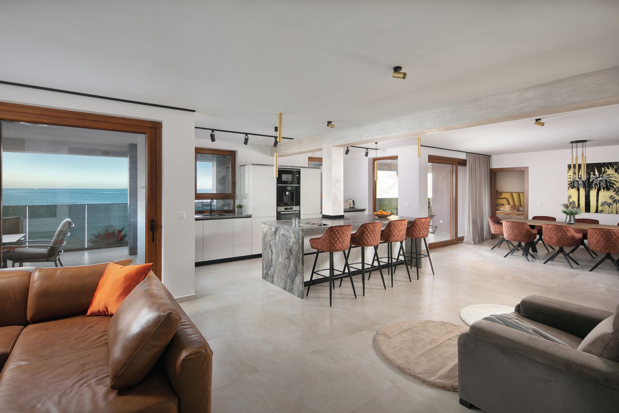 A modern living space with a kitchen, dining area, and a view of the sea.