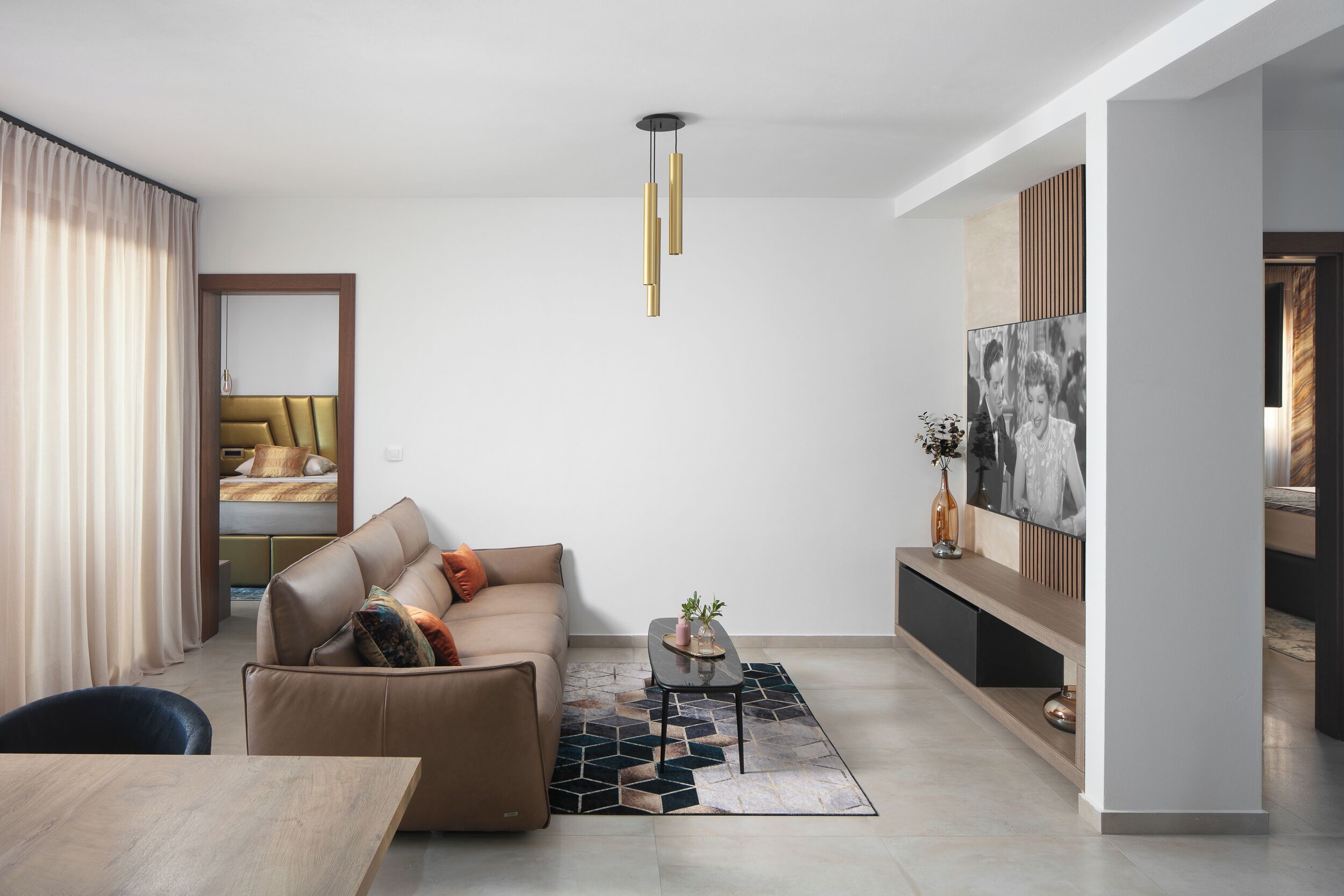 A modern living room with a sofa, coffee table, and a TV mounted on the wall.