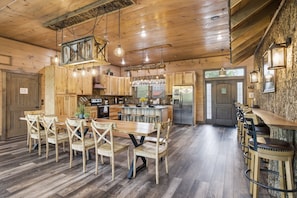 A rustic kitchen with wooden cabinets, a central island, and a bar area with stools.