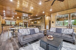 Un salón espacioso con un sofá grande de color gris, una mesa de centro y un comedor con sillas y mesa de madera.