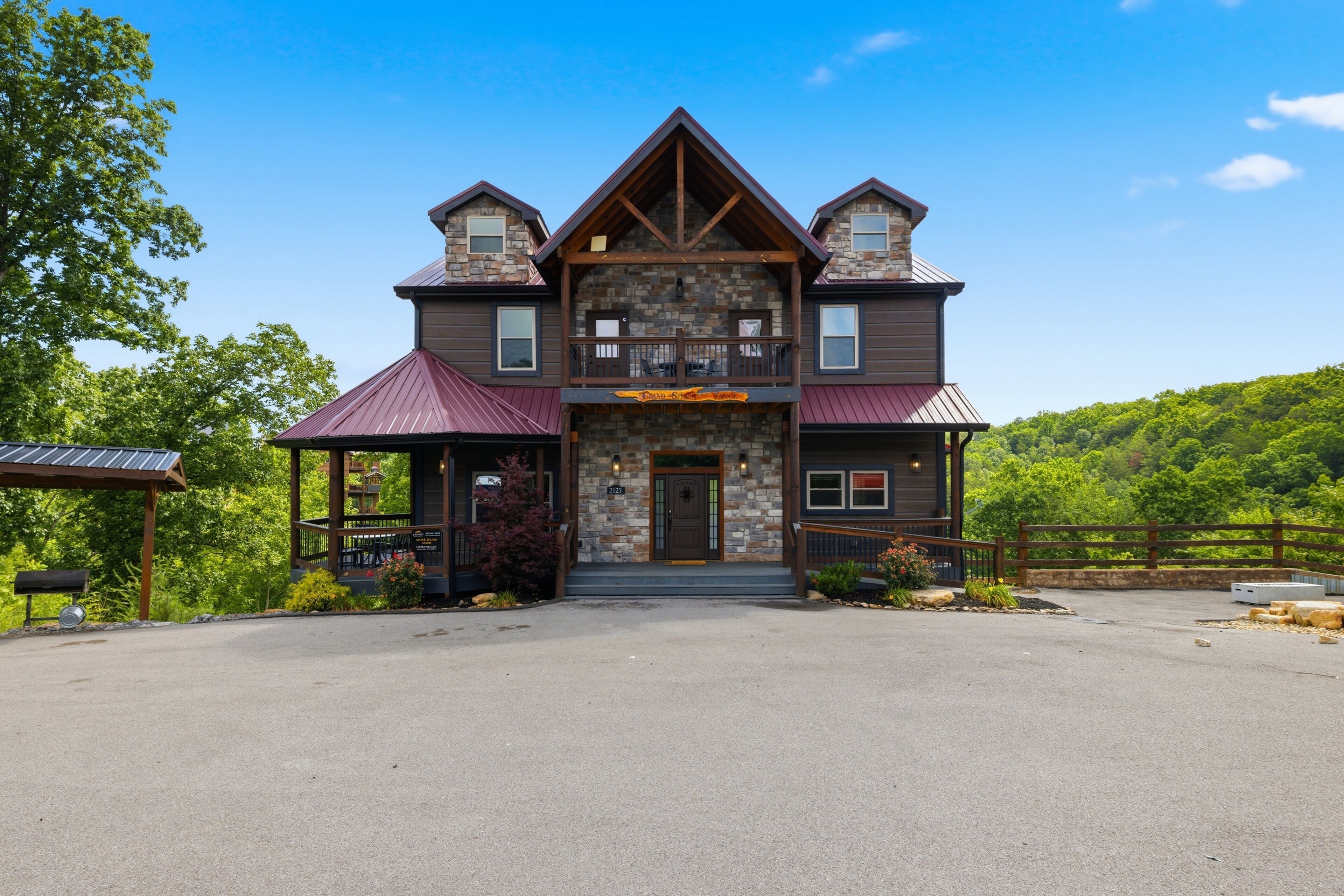 A two-story stone building with a central entrance, a covered porch on the left, and a fenced driveway.