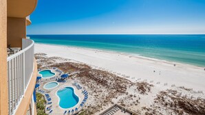 A beach view from a balcony with a pool area and beach chairs. - Phoenix Gulf Towers 1006 2 Bedroom Condo (Orange Beach)