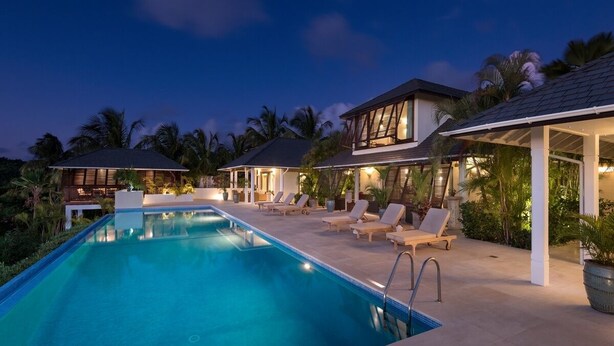 A poolside area with a swimming pool, lounge chairs, and a covered seating area. - Tom Tom 4 Bedroom Villa (Holetown)