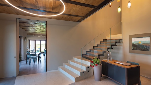 Un intérieur moderne comprenant un escalier, un comptoir d’accueil et un espace repas.