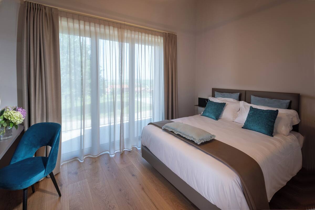 A hotel room with a bed, a chair, and a window with curtains.