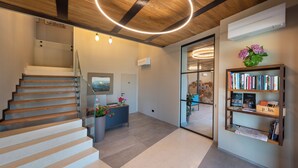 Un intérieur moderne avec un escalier en bois, un comptoir d’accueil et une bibliothèque.