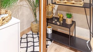 A modern kitchen with a black metal shelf holding kitchenware, a coffee maker, and a small plant. - Jaccuzzi Sauna Private Spa Paris (Montrouge)