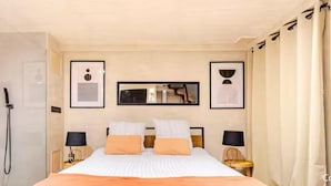 A hotel room with a bed, two bedside tables, a nightstand, a mirror, and a shower. - Jaccuzzi Sauna Private Spa Paris (Montrouge)