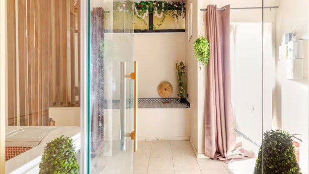 A modern bathroom with a glass partition, a shower area, and a small seating bench. - Jaccuzzi Sauna Private Spa Paris (Montrouge)