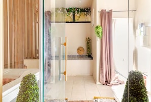 Une salle de bain moderne avec une cloison en verre, un espace douche et un petit banc.
