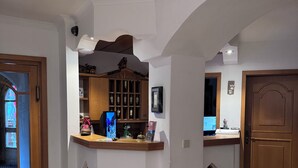 Un hall d’hôtel avec un comptoir d’accueil, un présentoir à bouteilles de vin et une porte en bois.