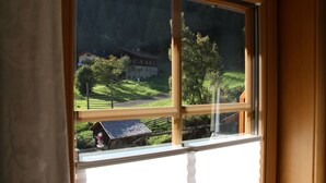 Une fenêtre donnant sur un paysage rural, avec une maison et une construction en bois.