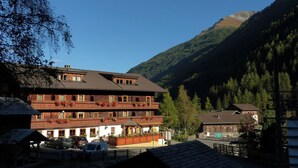 Un immeuble à plusieurs étages doté de balcons, d’un espace extérieur aménagé et couvert, et ayant une chaîne de montagnes en toile de fond.