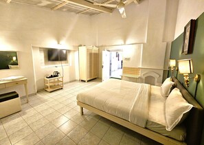 A hotel room with a large bed, a desk with a chair, a wardrobe, a television, and a bathroom visible through an open door. - iSTAYS The Colonial Villa Yercaud (Yercaud)