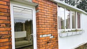 Parede exterior de tijolos com uma janela e porta brancas.