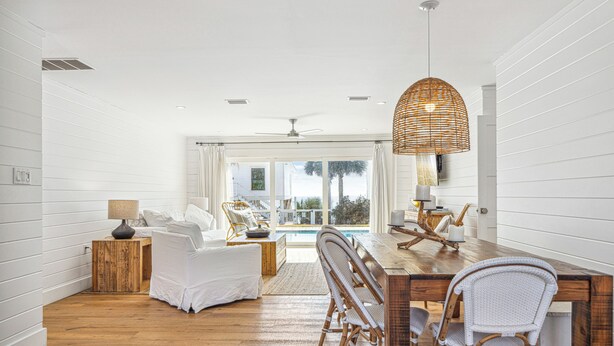 A spacious room with a wooden dining table, wicker chairs, and a large window overlooking a pool. - Private Beach Access, Private Pool/Hot Tub, Beach Service, and Pet Friendly! (Santa Rosa Beach)