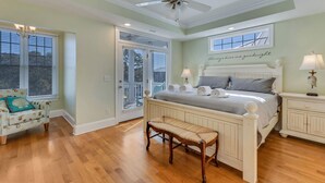 A bedroom with a bed, bedside tables, a chair, a ceiling fan, and a window with a view.