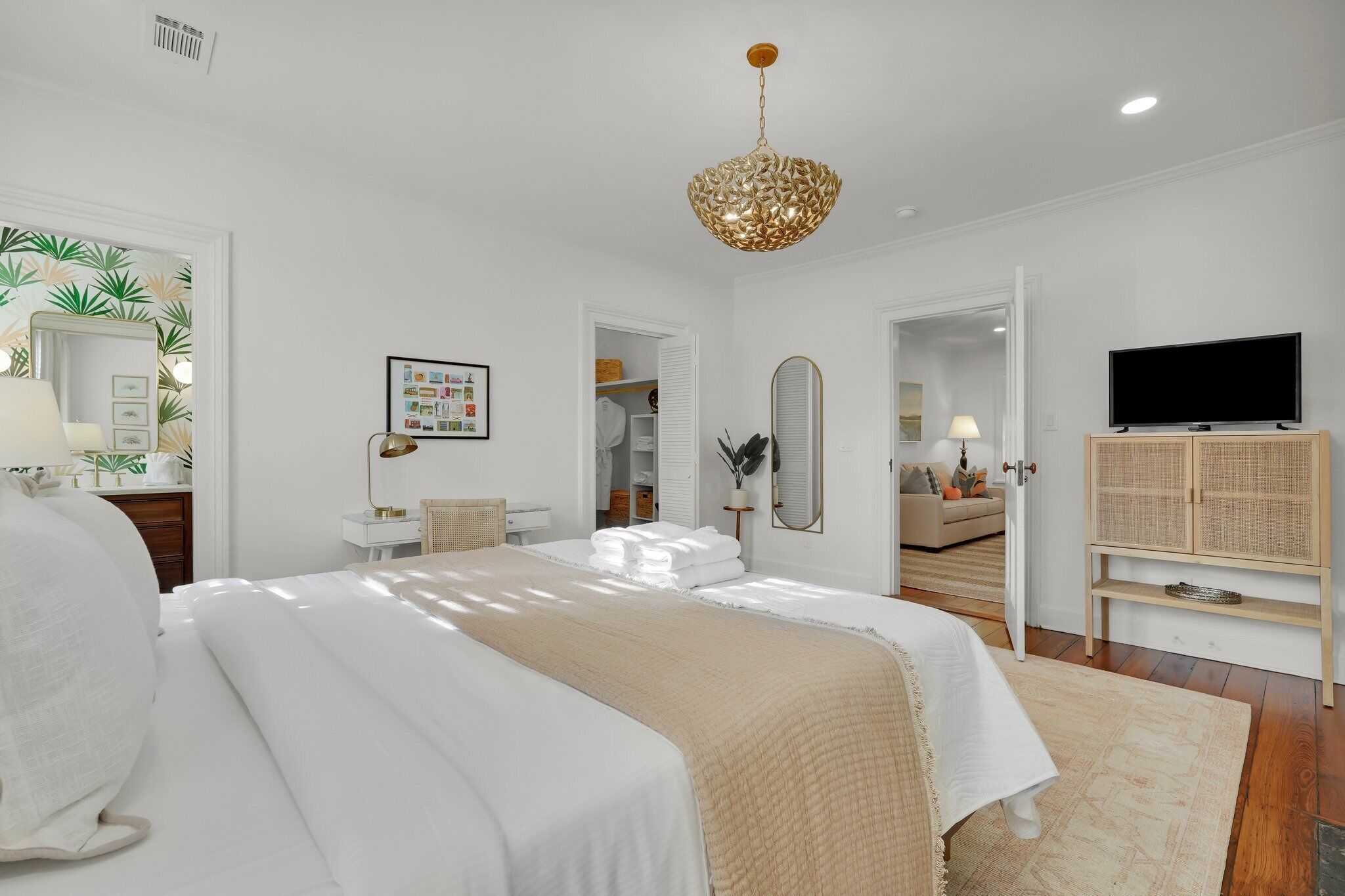 A bedroom with a large bed, a television, a wardrobe, and a bathroom visible through an open door.