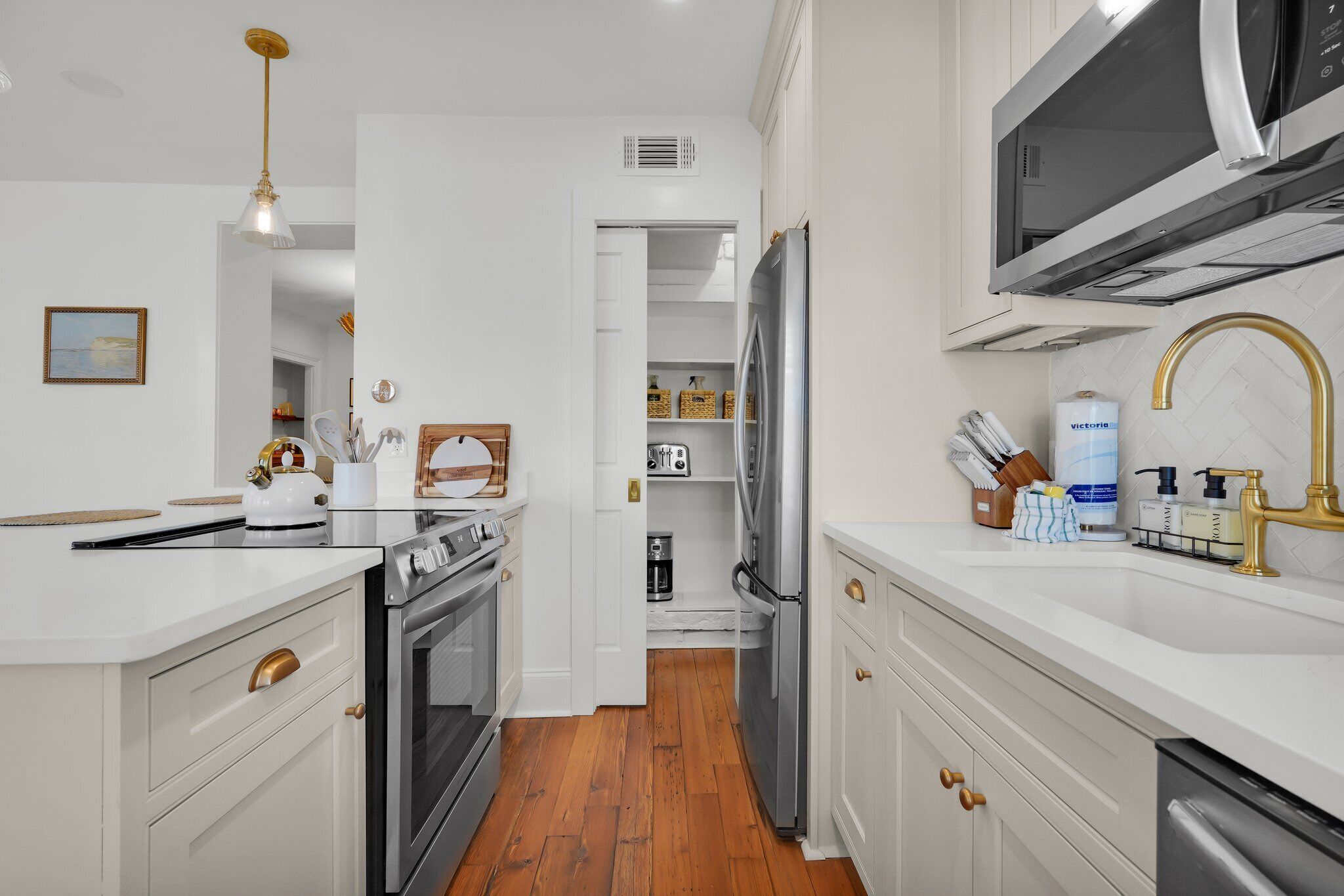 Una cocina moderna con armarios blancos, electrodomésticos de acero inoxidable y suelo de madera.