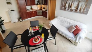 A compact living space with a dining area, kitchenette, and a sofa with a painting. - Apartment Lino with 2 bedrooms (Zadar)