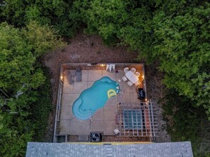 Vista aérea de um quintal com piscina, rodeado por árvores.