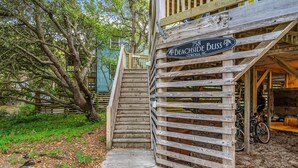 Un escalier en bois mène à un bâtiment sur lequel est affiché un panneau indiquant : « 758 Beachside Bliss, Corollia, Caroline du Nord ».