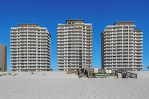 Three high-rise buildings with balconies, a sandy beach in the foreground, and a clear blue sky. - 🌴Summerwind Center 1204-Gulf Front, Near Navarre Beach Pier🌴 (Navarre Beach)