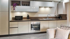 A modern kitchen with white cabinetry, a built-in microwave, a stove, and an oven. - Host & Stay | Chic Townhouse by the Docks (Liverpool)