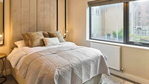 A bedroom with a bed, a window with a view, a radiator, and a bedside table. - Host & Stay | Chic Townhouse by the Docks (Liverpool)