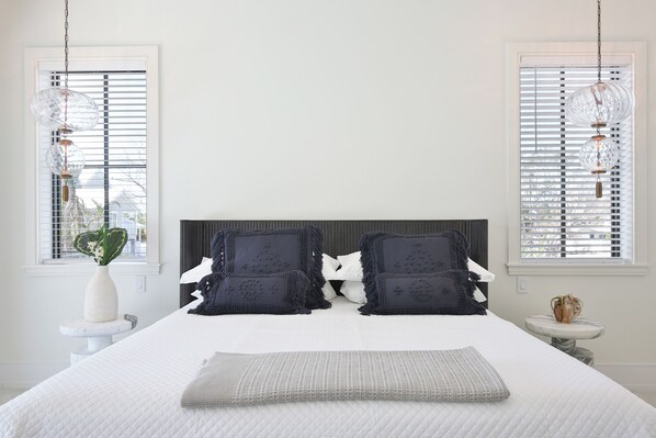 A neatly arranged bedroom with a large bed, two bedside tables, and a window with blinds. - 2 Min Walk to Beach, Bikes, Paddleboards, Heated Pool, Hot Tub, Fireplace (Holmes Beach)