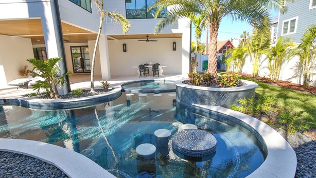 A modern outdoor pool area with a circular design, seating around the perimeter, and a patio with a table and chairs. - 2 Min Walk to Beach, Bikes, Paddleboards, Heated Pool, Hot Tub, Fireplace (Holmes Beach)