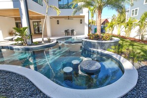 A modern outdoor pool area with a circular design, seating around the perimeter, and a patio with a table and chairs. - 2 Min Walk to Beach, Bikes, Paddleboards, Heated Pool, Hot Tub, Fireplace (Holmes Beach)