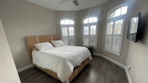 A bedroom with a large bed, a ceiling fan, and three windows with shutters. - Beautiful 3-bedroom house in a gated community in Estero. Pool, Spa, Fitness (Fort Myers)